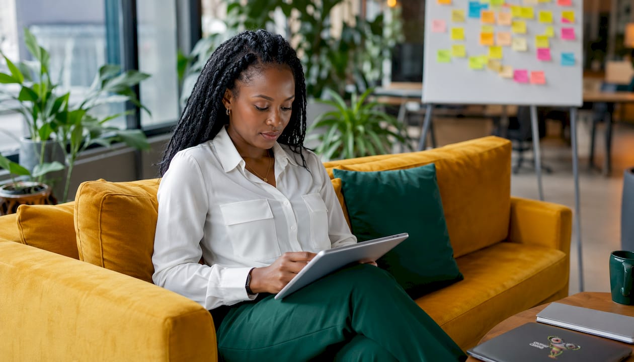 Une femme cadre consulte sa tablette sur son bureau dans un espace de travail contemporain.