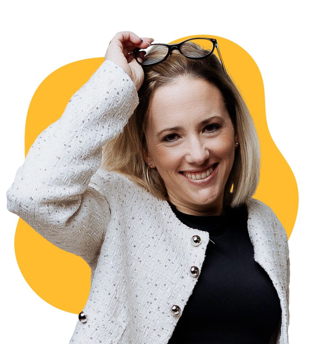 Photo d'une jeune femme souriante aux cheveux blonds, portant une veste blanche et un haut noir